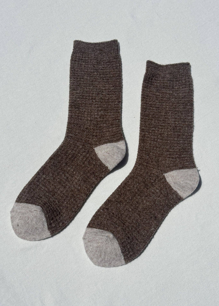 Pair of brown socks with gray toes and cuffs on a light gray background