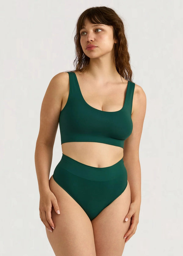 Woman wearing a green swimsuit against a white background