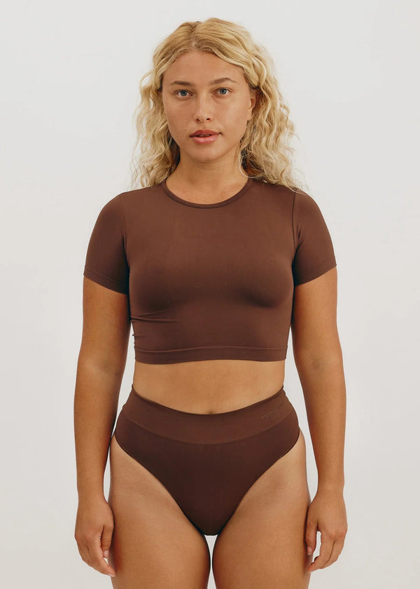 Woman wearing a brown two-piece outfit on a white background