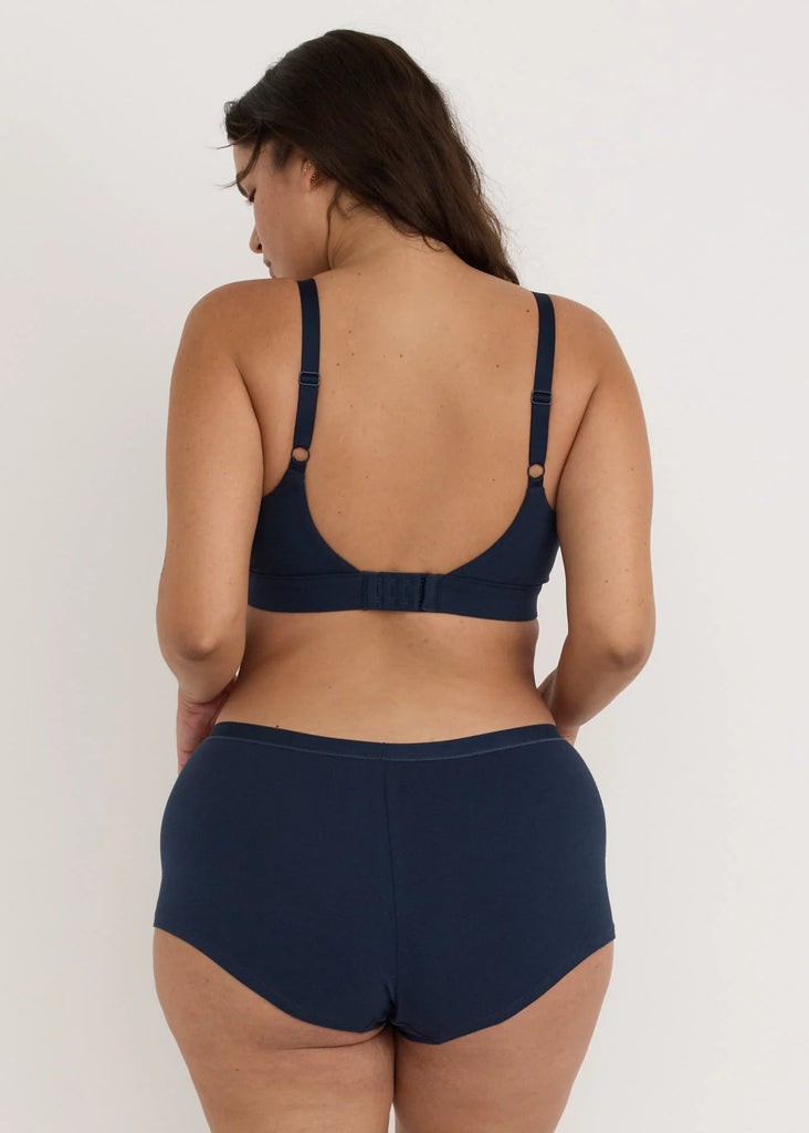 Person wearing a navy blue bikini set on a white background