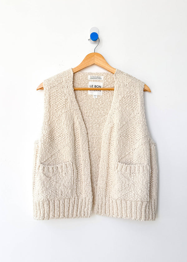 Beige knitted vest on a hanger against a white background