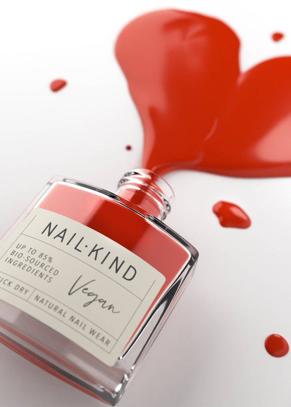 Red nail polish bottle with 'Nail Kind' label and heart-shaped red paint splashes on a white background