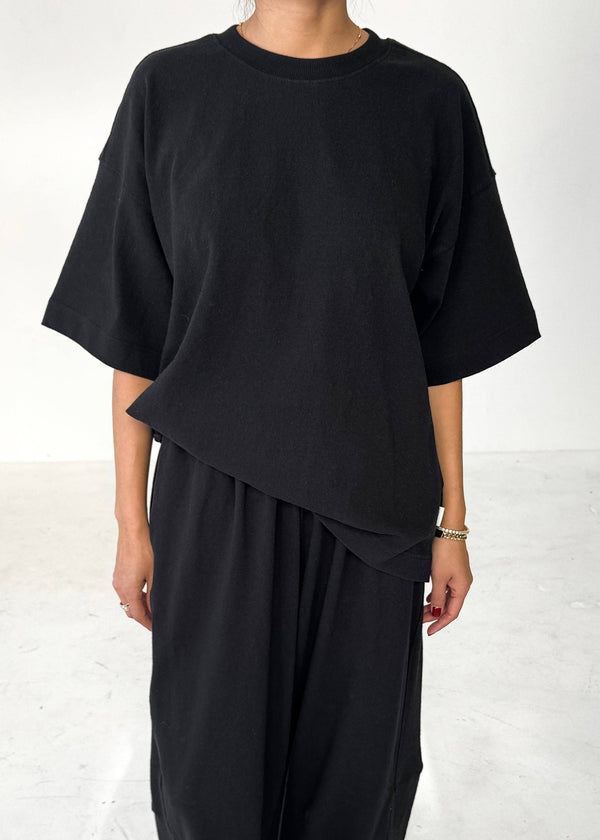 Person wearing a black outfit with an asymmetrical design on a white background