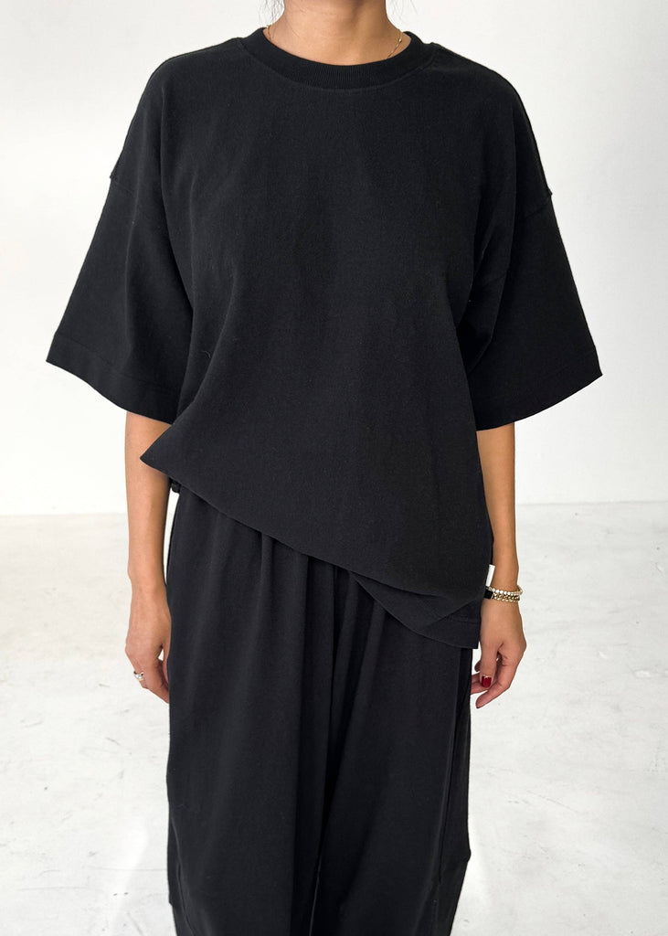 Person wearing a black outfit with an asymmetrical design on a white background