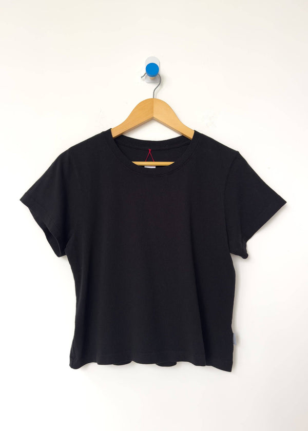 Black t-shirt on a wooden hanger against a white background
