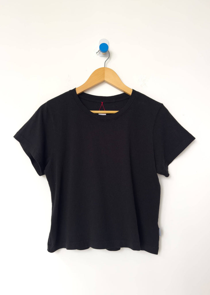 Black t-shirt on a wooden hanger against a white background