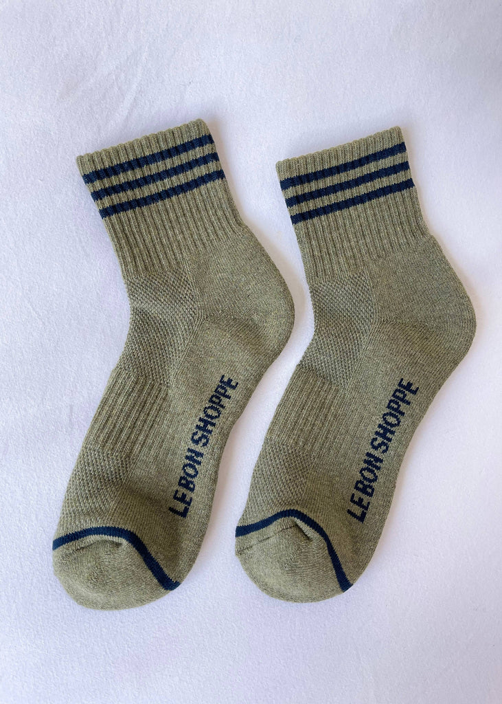 Pair of green socks with blue stripes and 'Le Bon Shoppe' branding on a white background