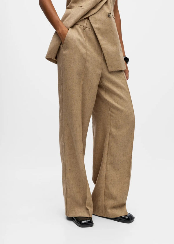 Person wearing a beige suit with wide-leg pants on a white background