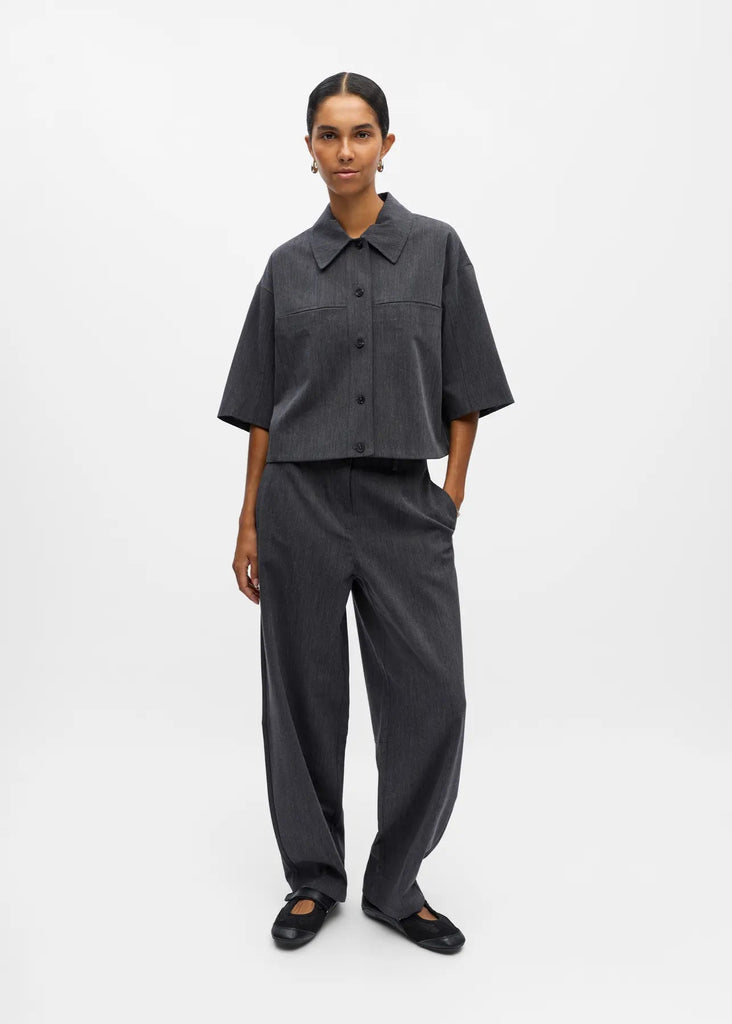 Person wearing a dark gray shirt and pants on a white background