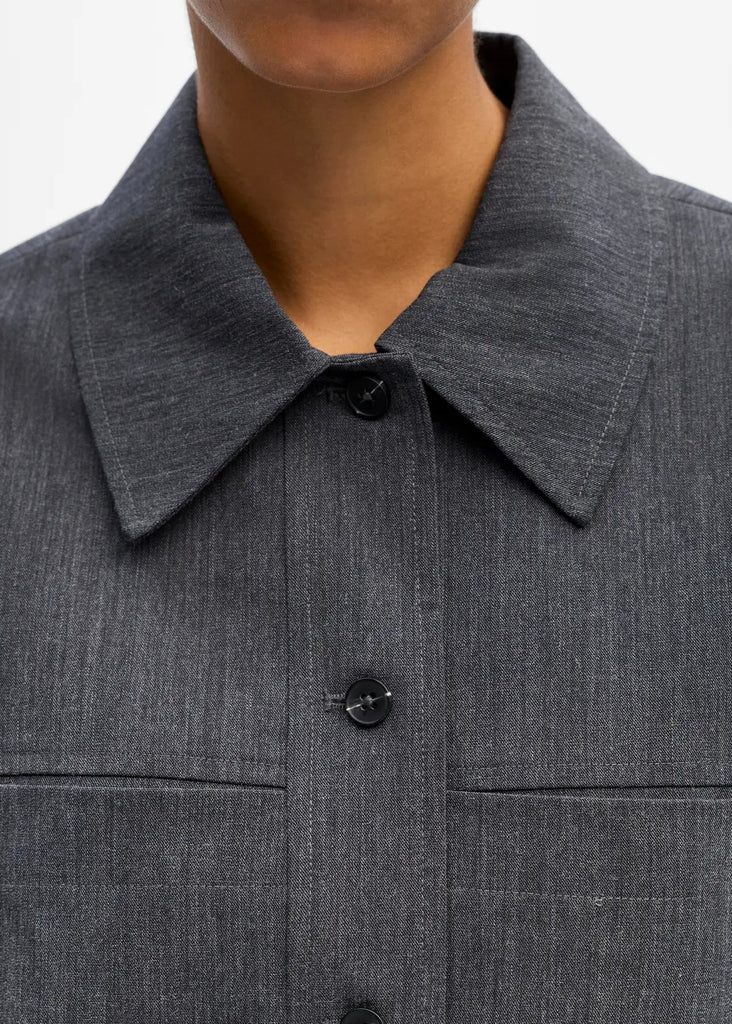Close-up of a gray jacket with a collar and buttons on a neutral background