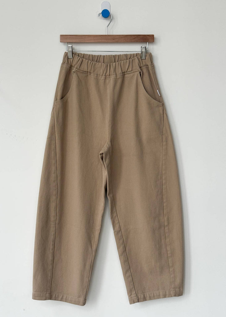 Beige pants hanging on a wooden hanger against a white background