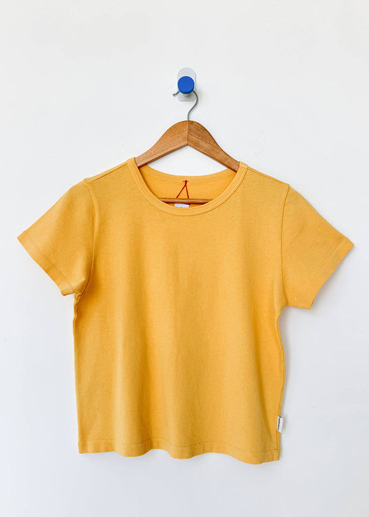 Yellow t-shirt on a wooden hanger against a white background