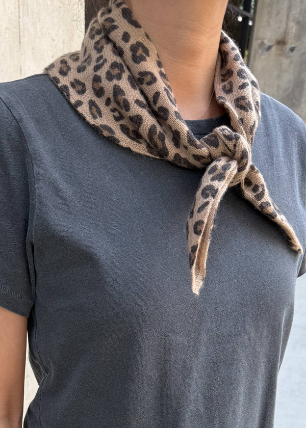 Person wearing a gray shirt with a leopard print scarf around their neck.