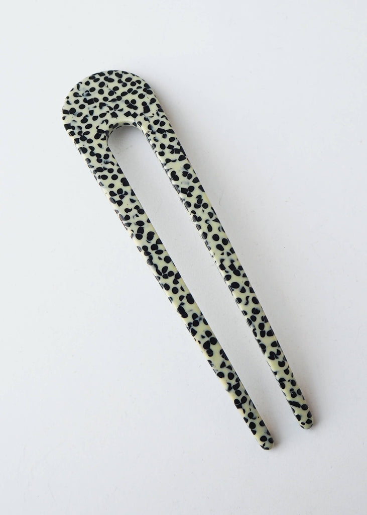 Pair of black and white spotted hair clips on a light gray background