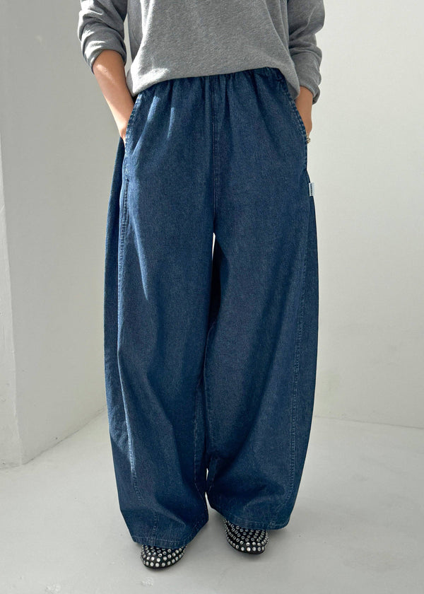 Person wearing blue wide-leg pants and a gray top on a white background