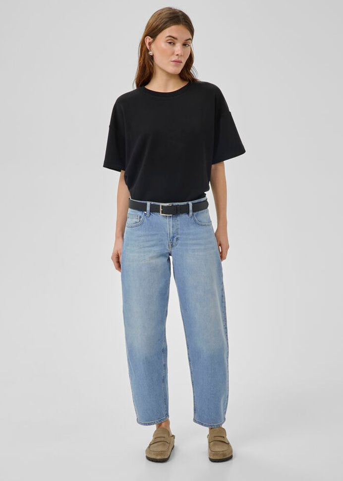 Woman wearing a black t-shirt and light blue jeans on a gray background