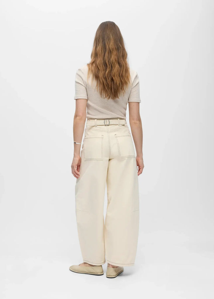 Person wearing a beige top and wide-leg pants on a white background