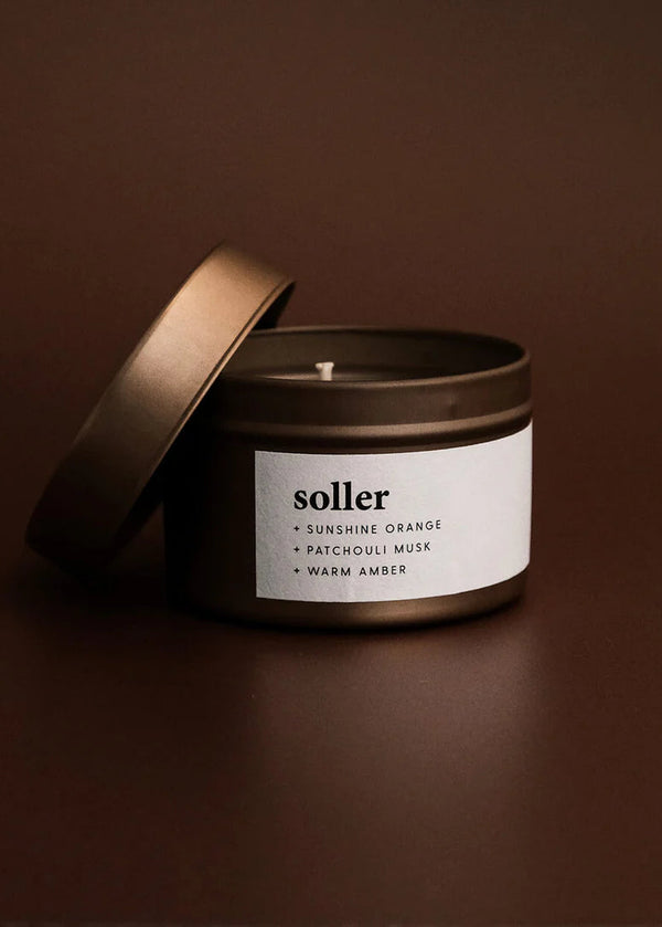 Soller candle in a black tin with a brown lid on a brown background